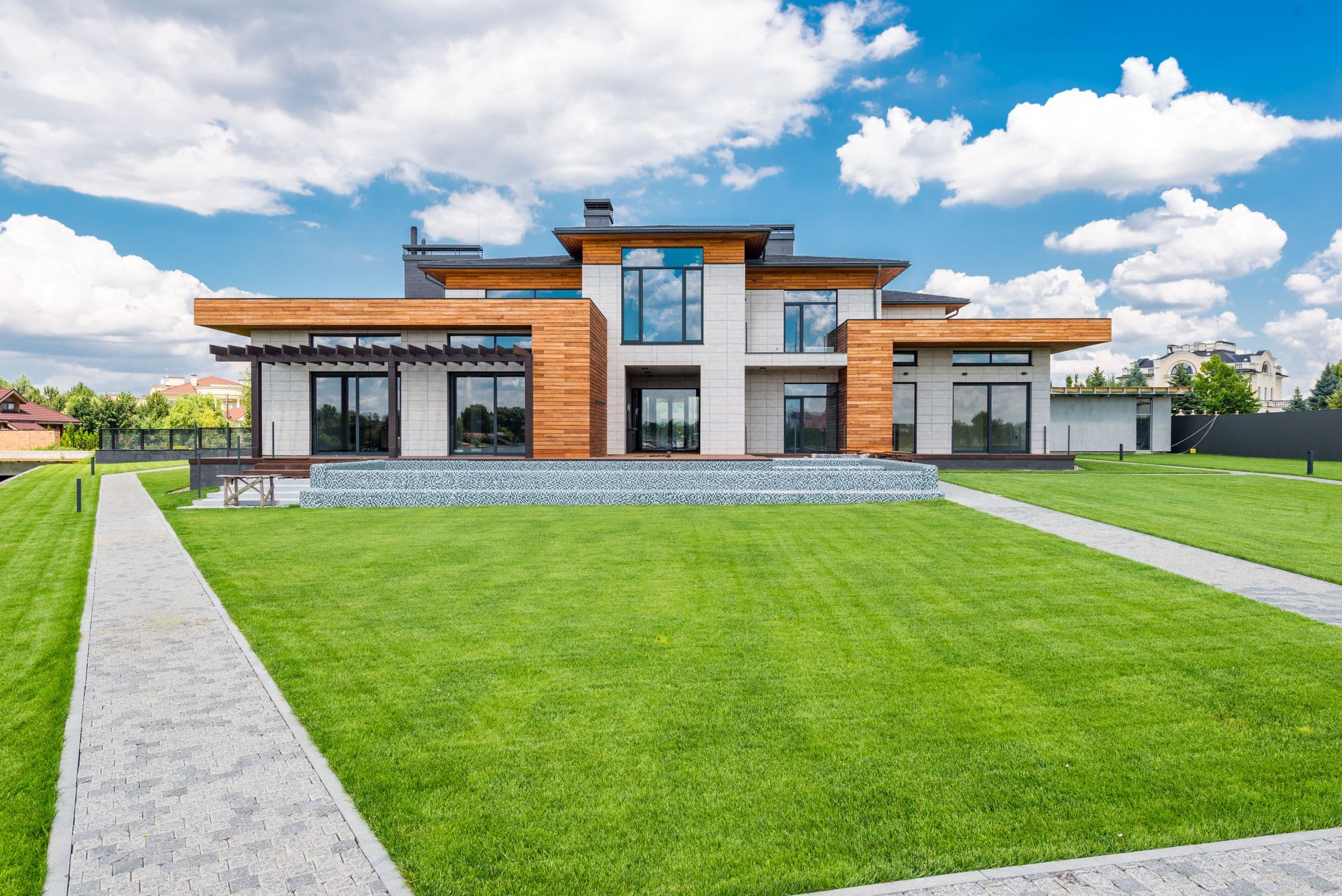 Maison contemporaine rénovée, façade bois et grandes baies vitrées éclairées en fin de journée